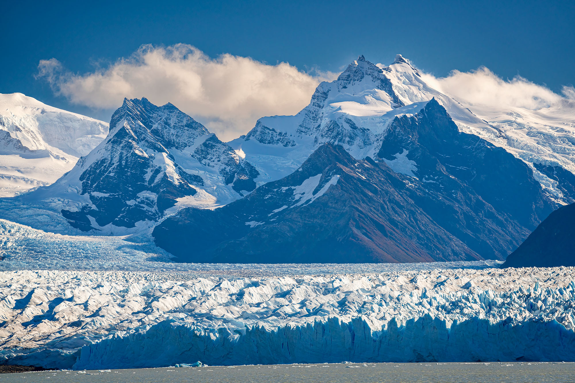Moreno Glacier and Towering Peaks In this striking image, we gaze upon the grandeur of the Moreno Glacier in Patagonia, Argentina. The glacier sprawls before us...