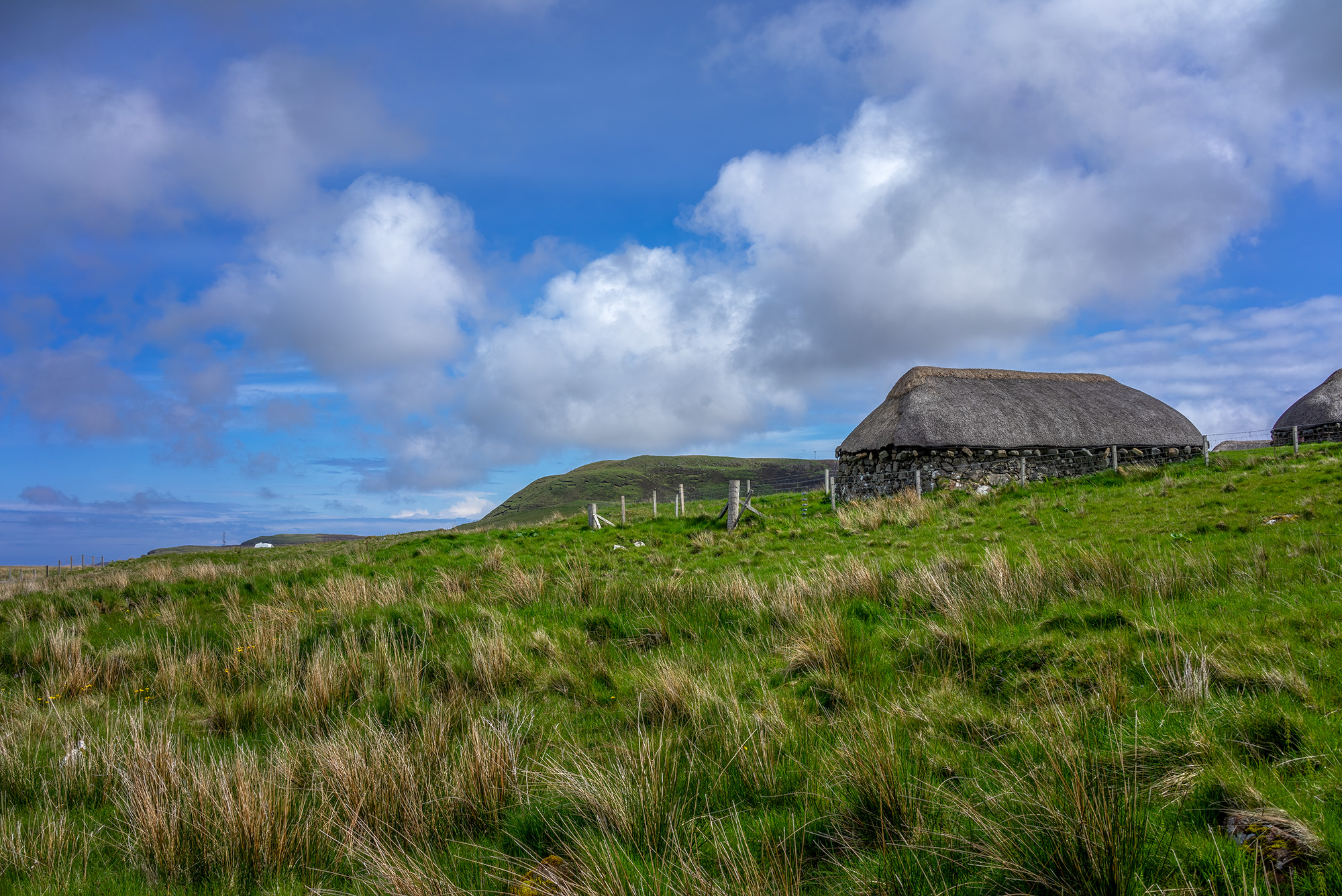 This photograph captures the essence of rural life on the Isle of Skye, Scotland. The traditional farmhouse, nestled amidst the...