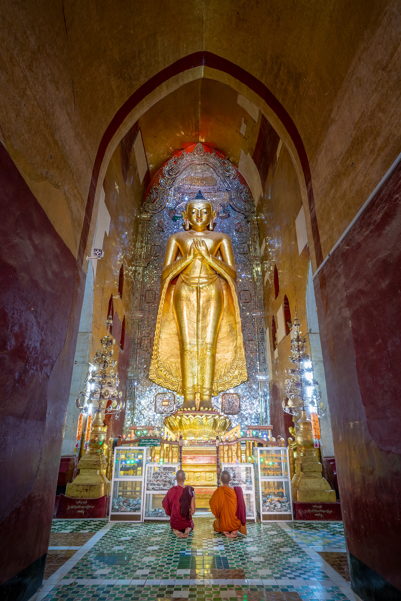 Inside a grand temple of Bagan, Myanmar, "Devotion in Golden Hues" reveals a striking vertical composition. At the heart of the...