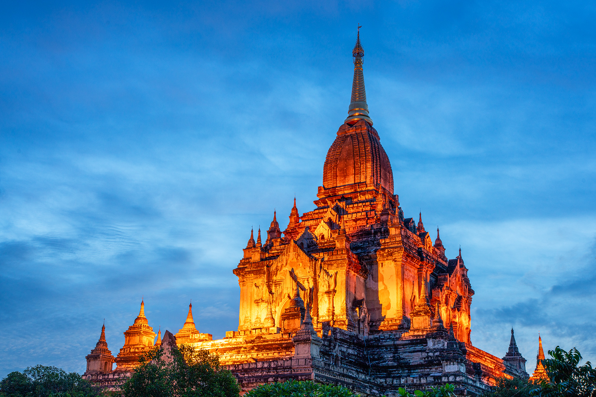 In "Elegant Radiance," Nanda Temple stands as a beacon of exquisite craftsmanship during Bagan's tranquil blue hour. Against...