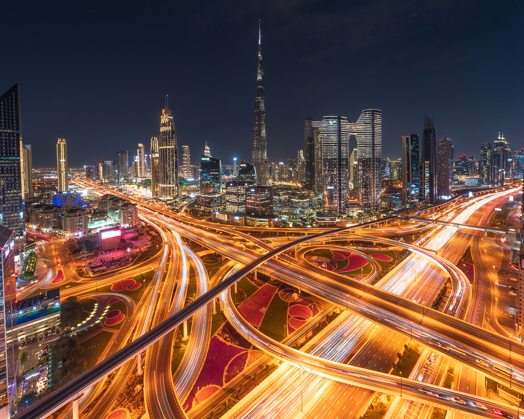 This photograph, taken at night in Dubai, UAE, presents a sprawling and intricate highway interchange, brilliantly illuminated...