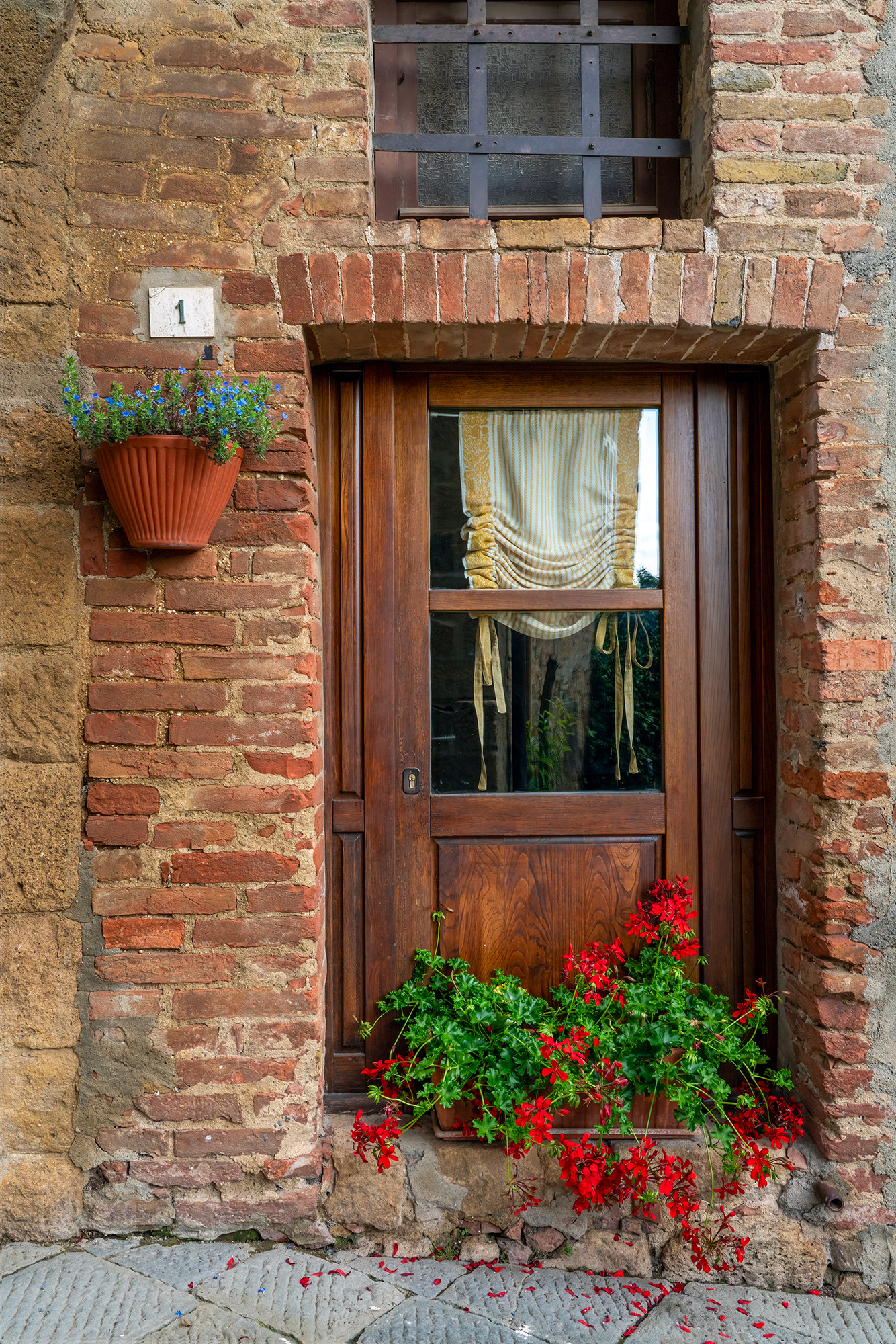A warm and inviting doorfront photograph from Montepulciano, Italy, captures the essence of this charming town. The rustic door...