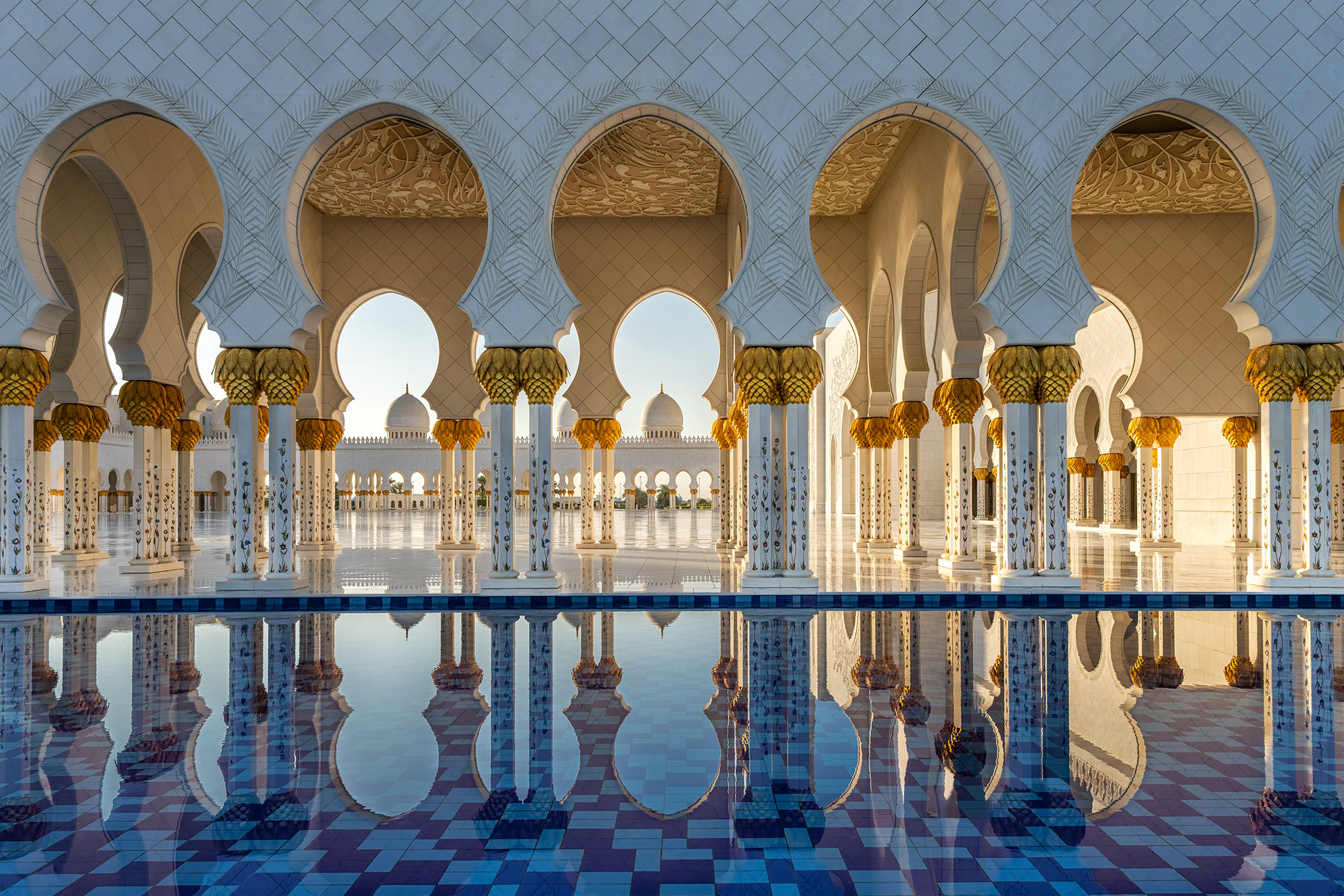 In this image captured at the Sheikh Zayed Grand Mosque in Abu Dhabi, UAE, the viewer is transported through a passage of five...