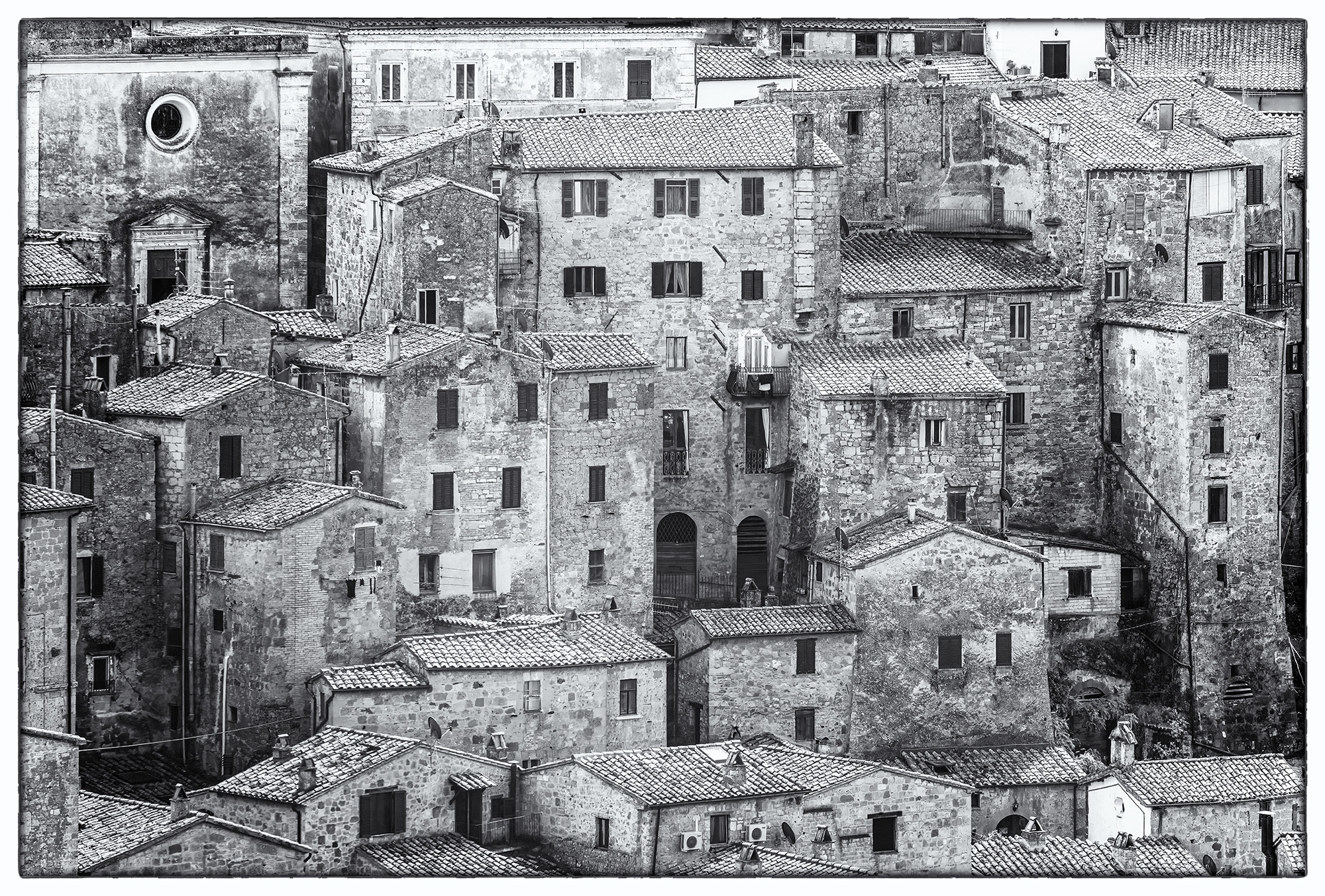 In this Black and White image, Pitigliano, Tuscany, Italy, reveals its medieval charm. This photo, devoid of sky, portrays a...