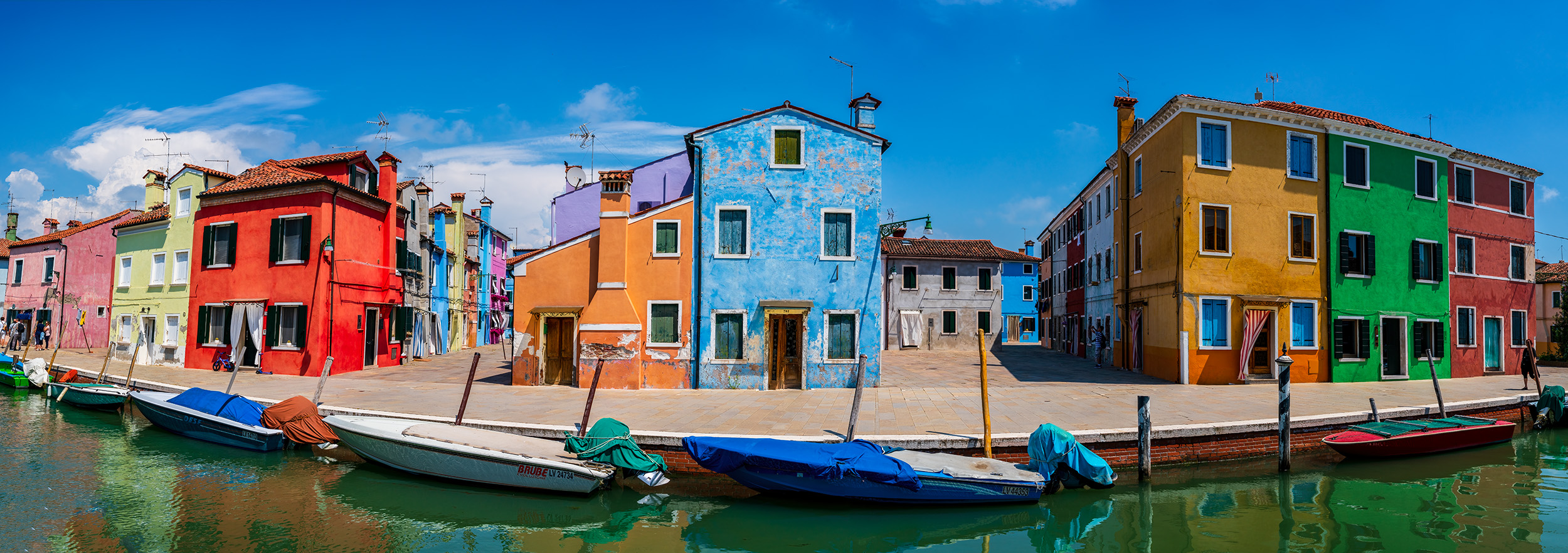 A panoramic image showcases the vibrant island of Burano, Italy, adorned with a multitude of brilliant, multi-colored homes....