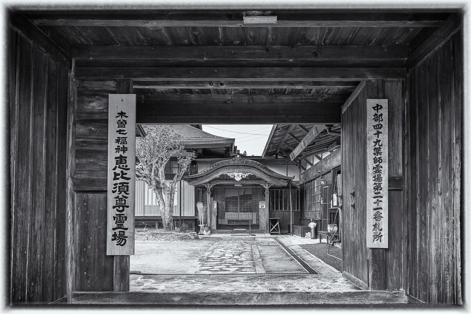 Gate to Tranquility In "Gate to Tranquility," a striking black and white composition captures the entrance to a hilltop temple in Tsumago, Japan....