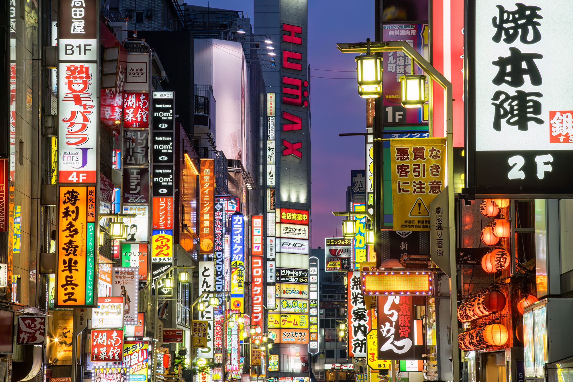 In the heart of Shinjuku, Tokyo, this nighttime shot unveils a bustling urban thoroughfare illuminated by a cacophony of vibrant...