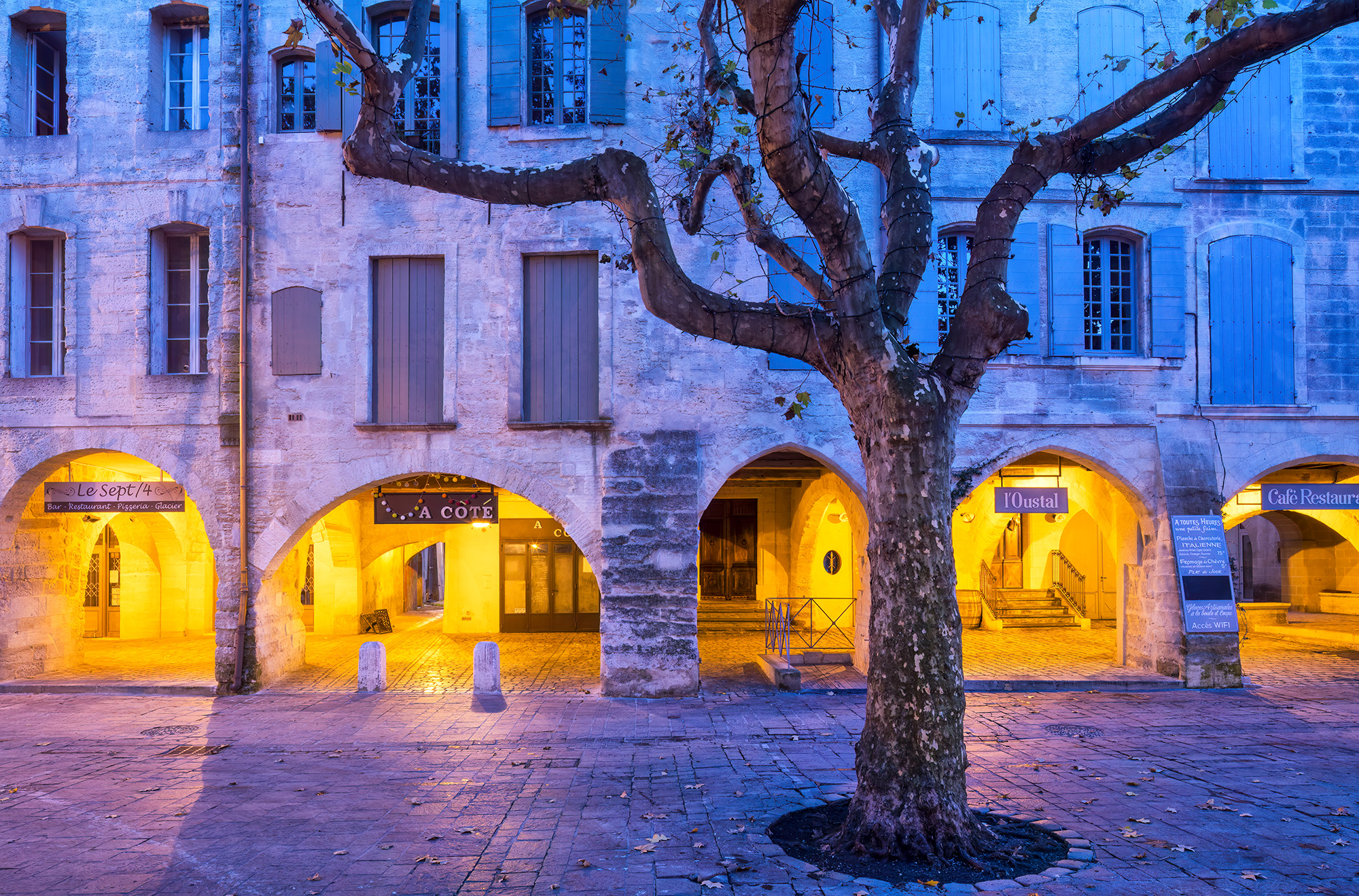 In this blue hour scene of Uzes, France, the gold arches offer a touch of "sunlight" amid the prevailing blue and purple tones...