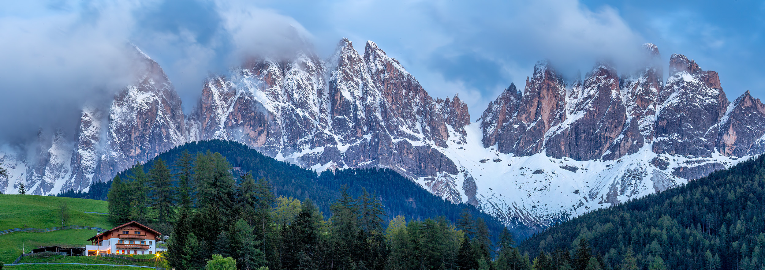 As daylight fades over Val di Funes in Italy's Sud Tyrol region, this panoramic image captures the magic of the moment. A cozy...