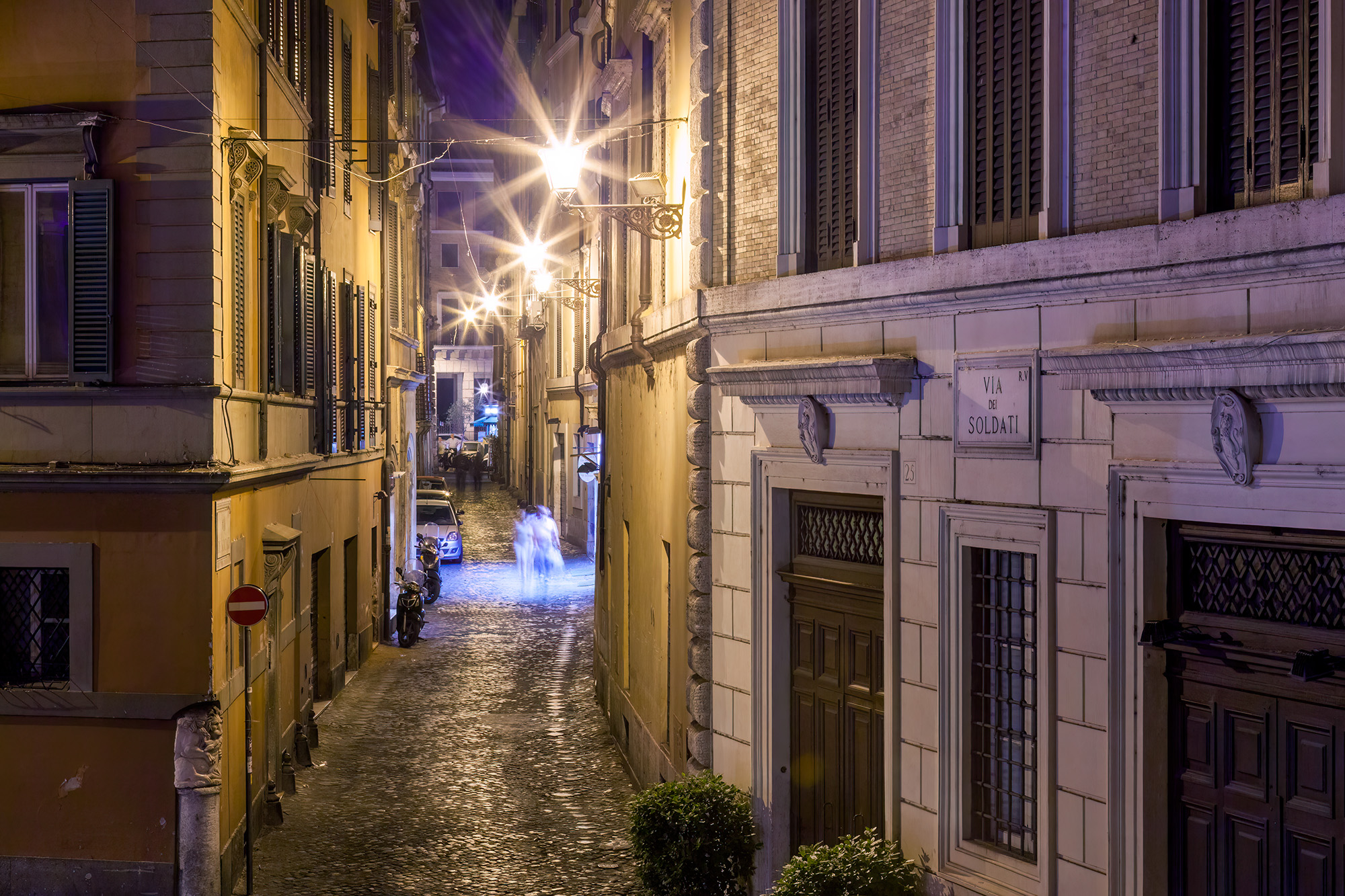 This nighttime image of Via de Soldati in Rome, Italy, paints a scene of charm and romance. A cobbled street stretches ahead...