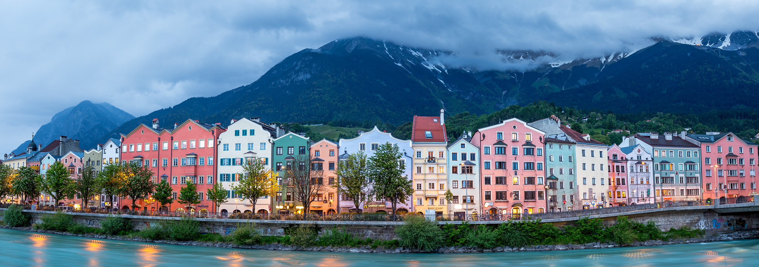 Innsbruck's Riverside Elegance "Innsbruck's Riverside Elegance" presents an iconic view of the city's renowned 'row of houses' along the picturesque Inn River...