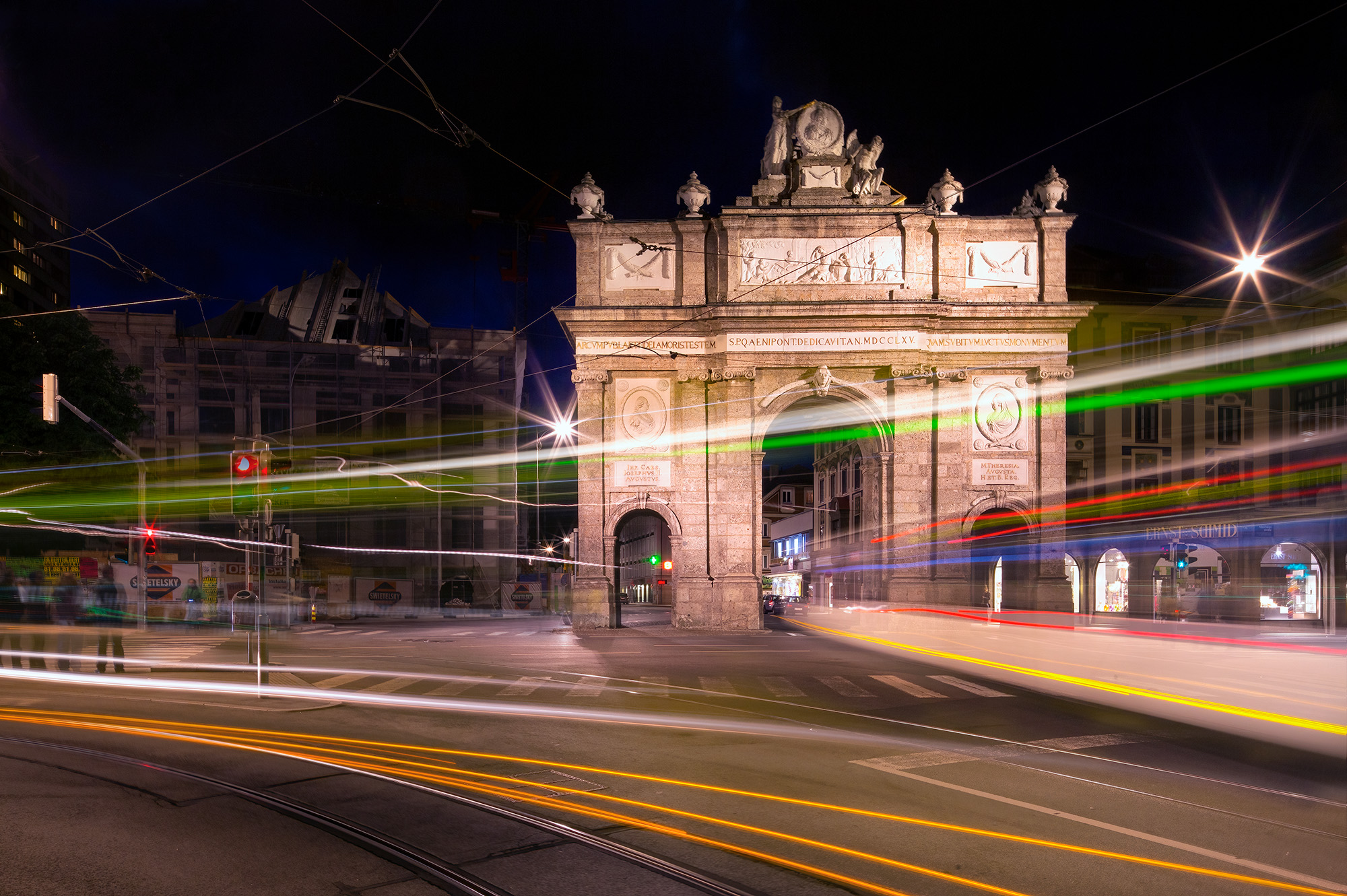 Trams through Triumphal Arch As the night descends upon Innsbruck, the city's heartbeat continues to pulse with life. This captivating image captures the...