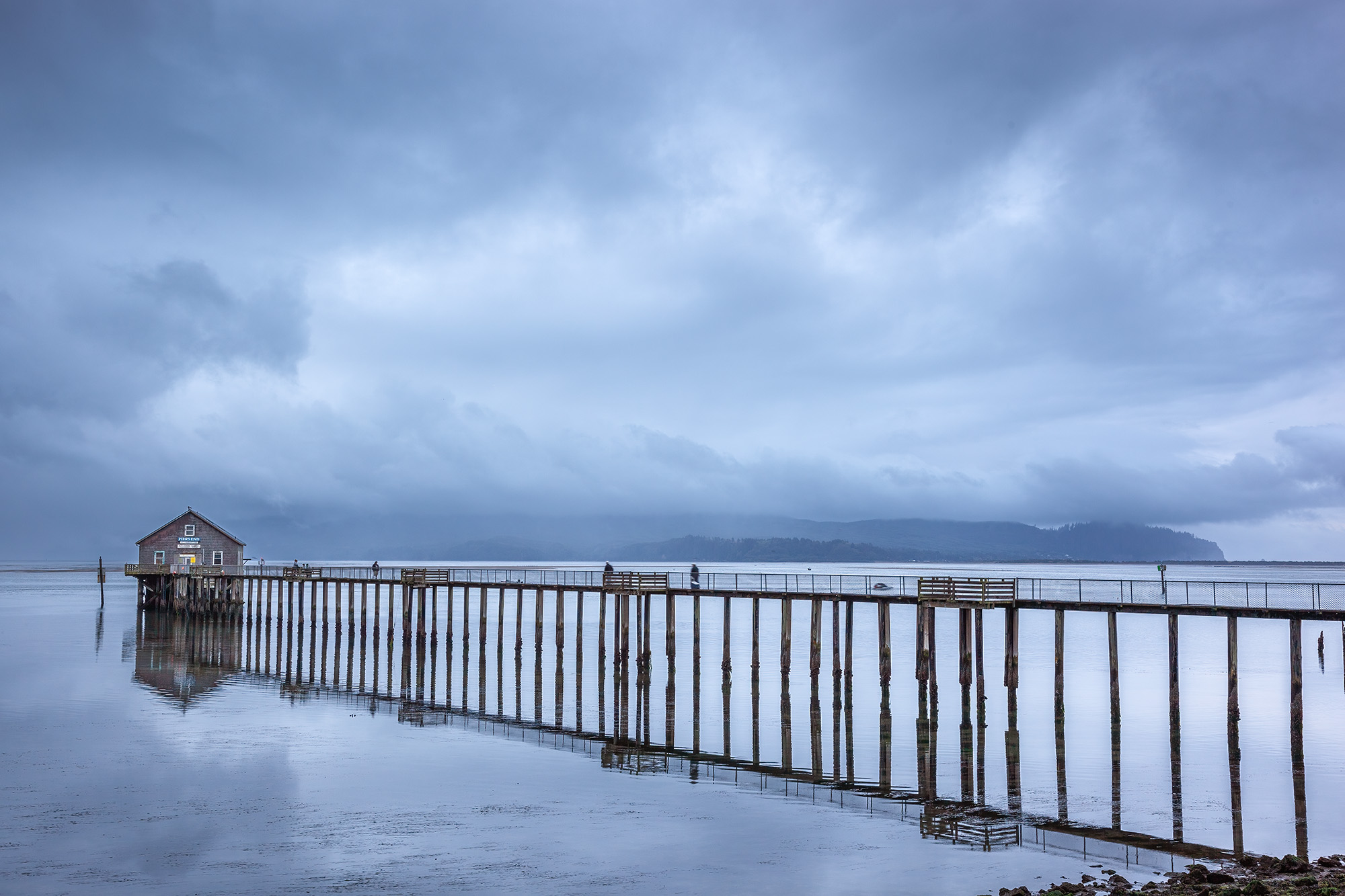 Piers End In Garibaldi, Oregon, this photograph captures the essence of coastal charm. At the end of a weathered pier stands a quaint building...