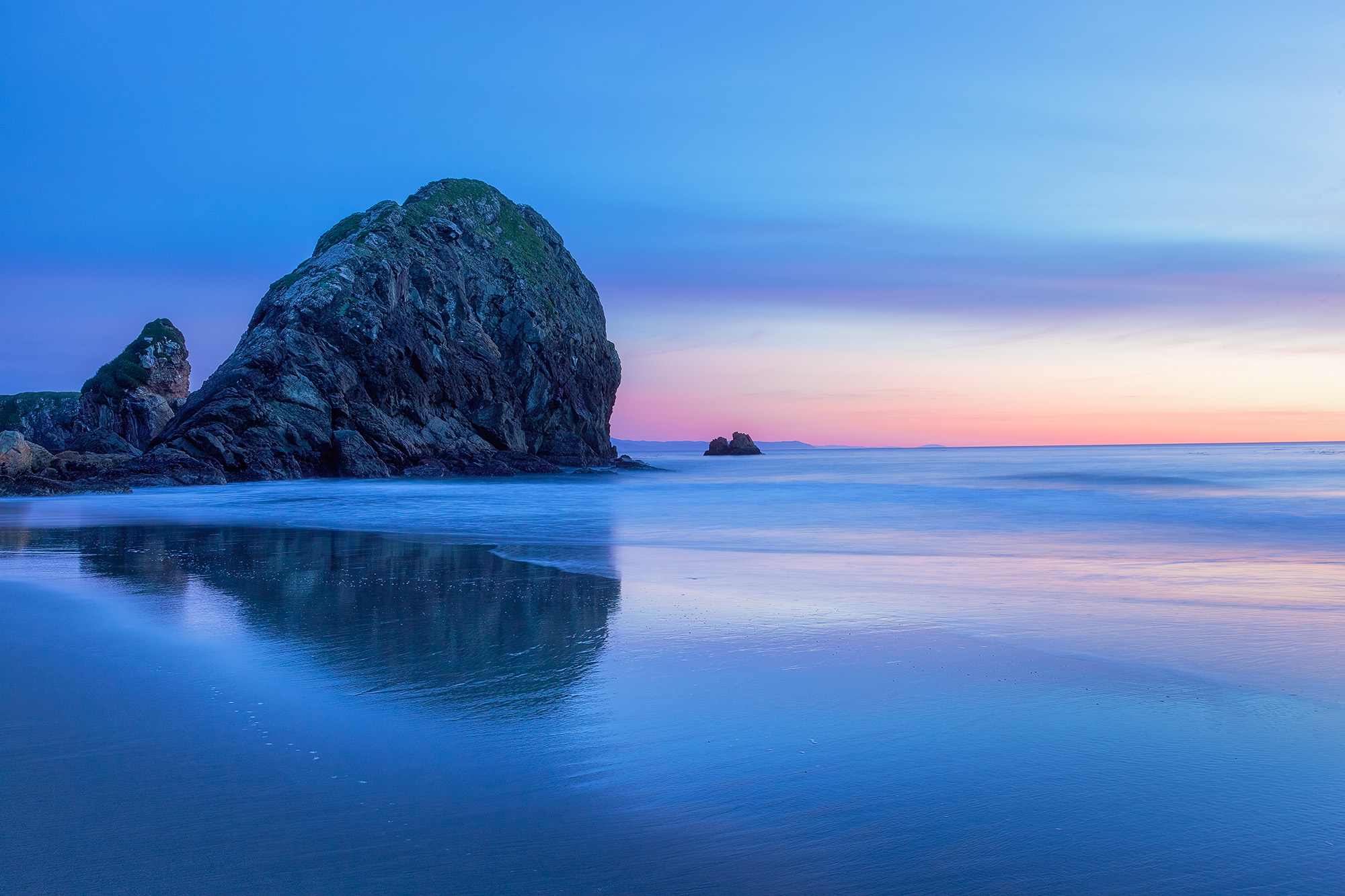 This image, captured near Brookings on the Oregon coast, frames the iconic Haystack Mountain against the sandy beach. A serene...