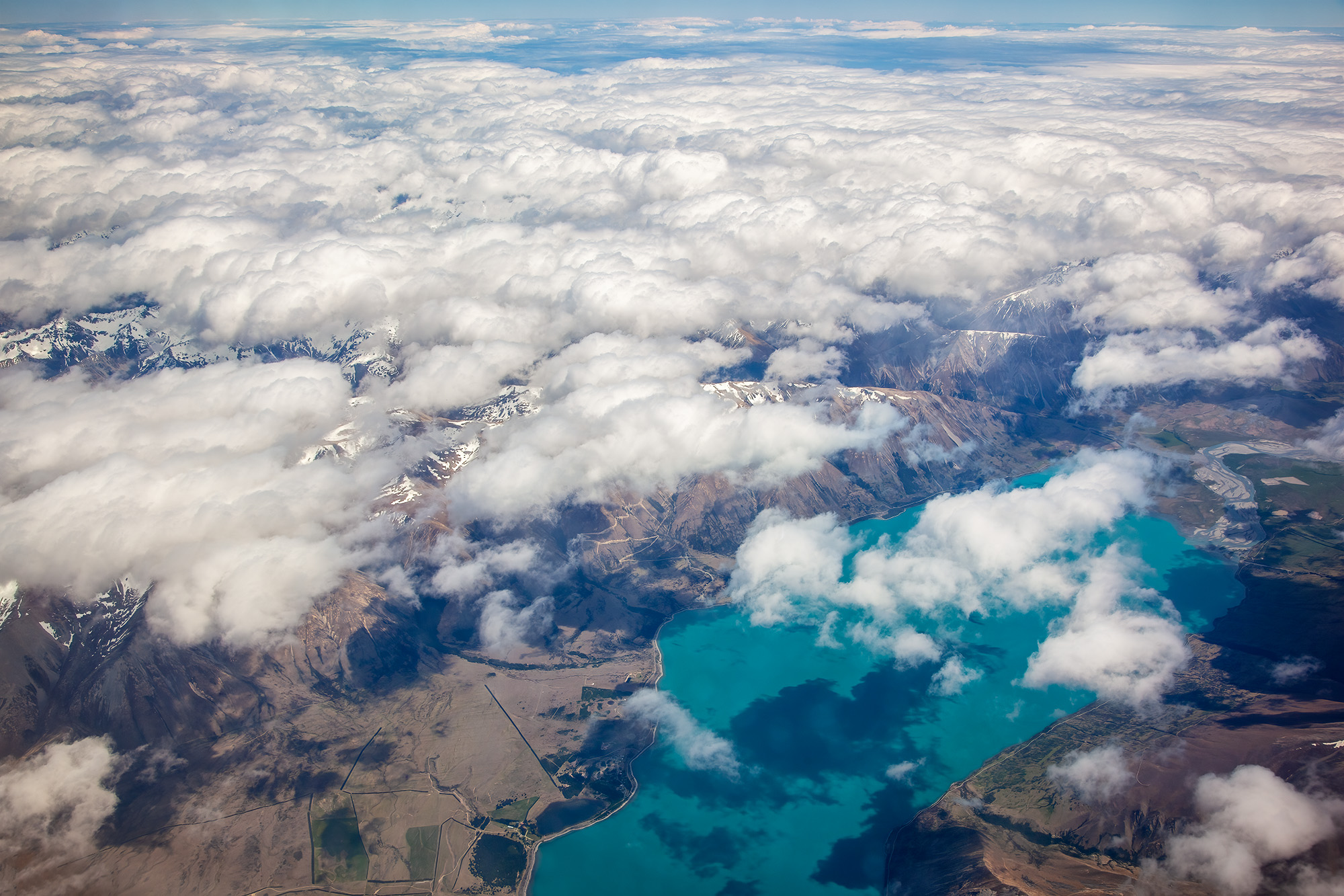 Captured from the window of a plane flying high above New Zealand's Southern Alps, this image presents a breathtaking symphony...
