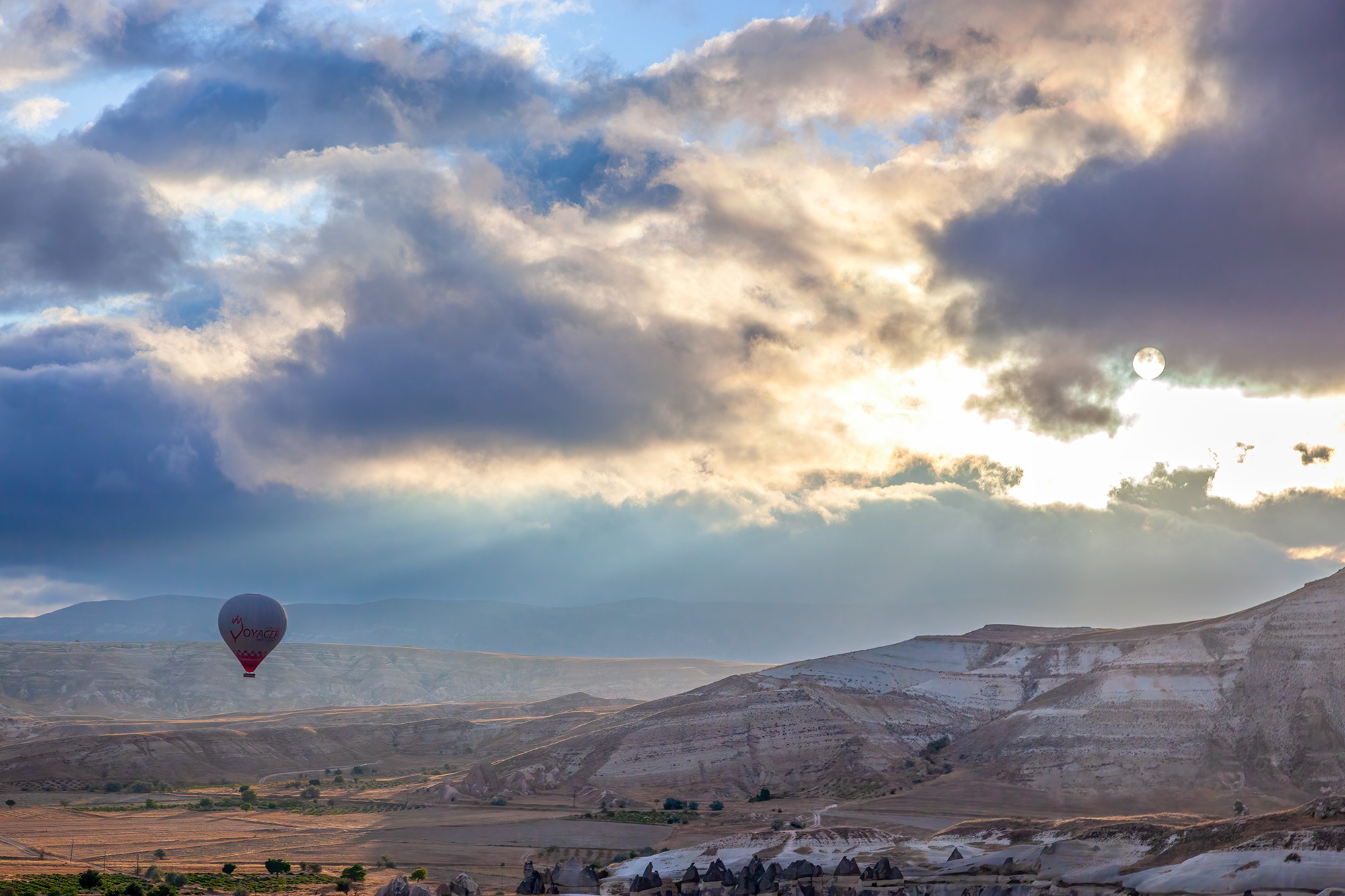 In this image, a hot air balloon rises into the sky above Cappadocia, Turkey, embracing the radiant embrace of the sunrise. The...