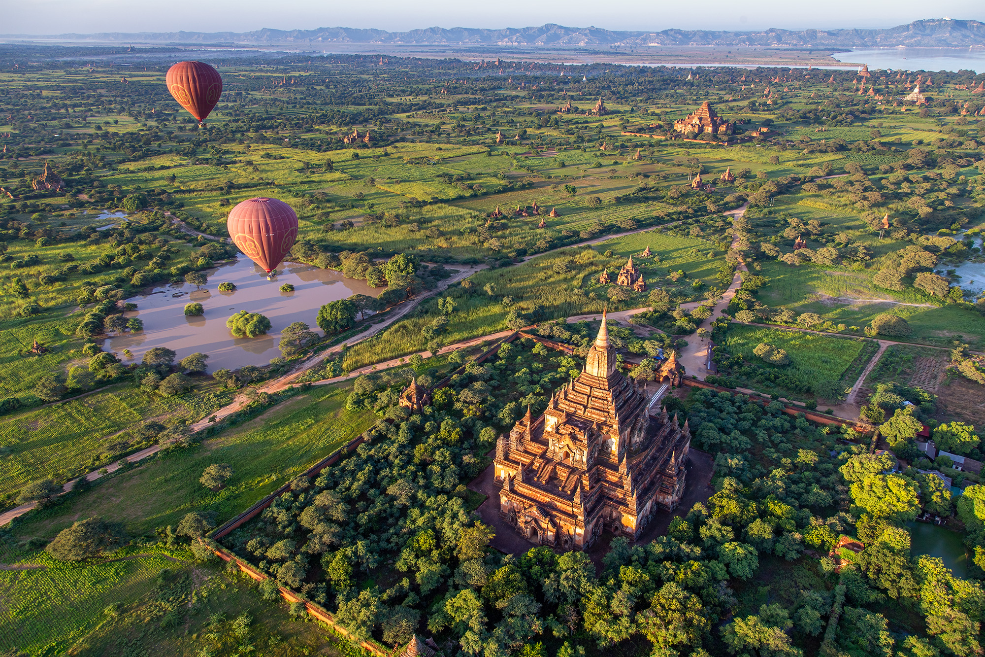 Captured from a hot air balloon gracefully gliding over Bagan, Myanmar, this aerial view reveals the vast expanse of ancient...