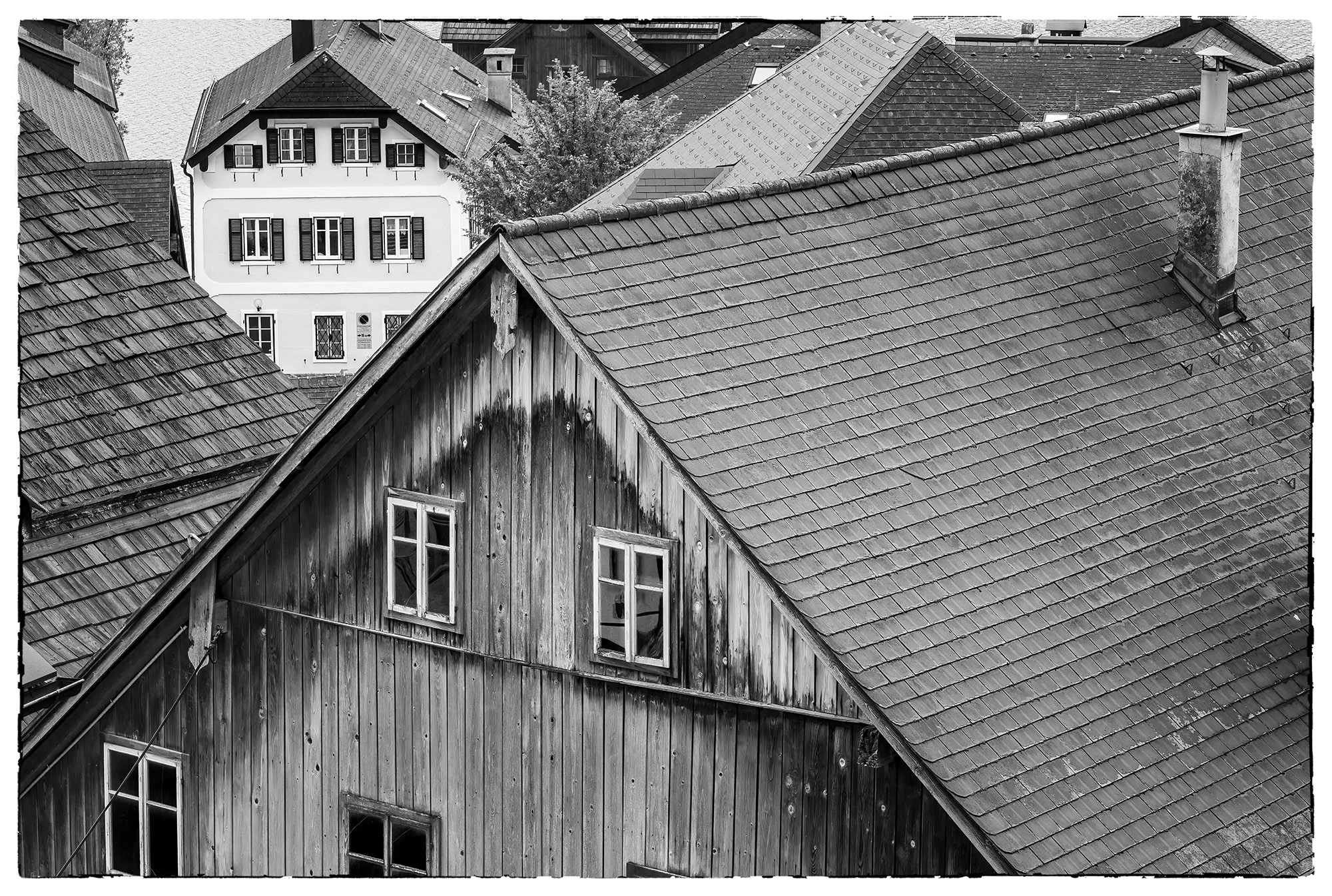This black & white photograph captures the essence of a quaint village nestled in Austria's picturesque Lake District. The charming...