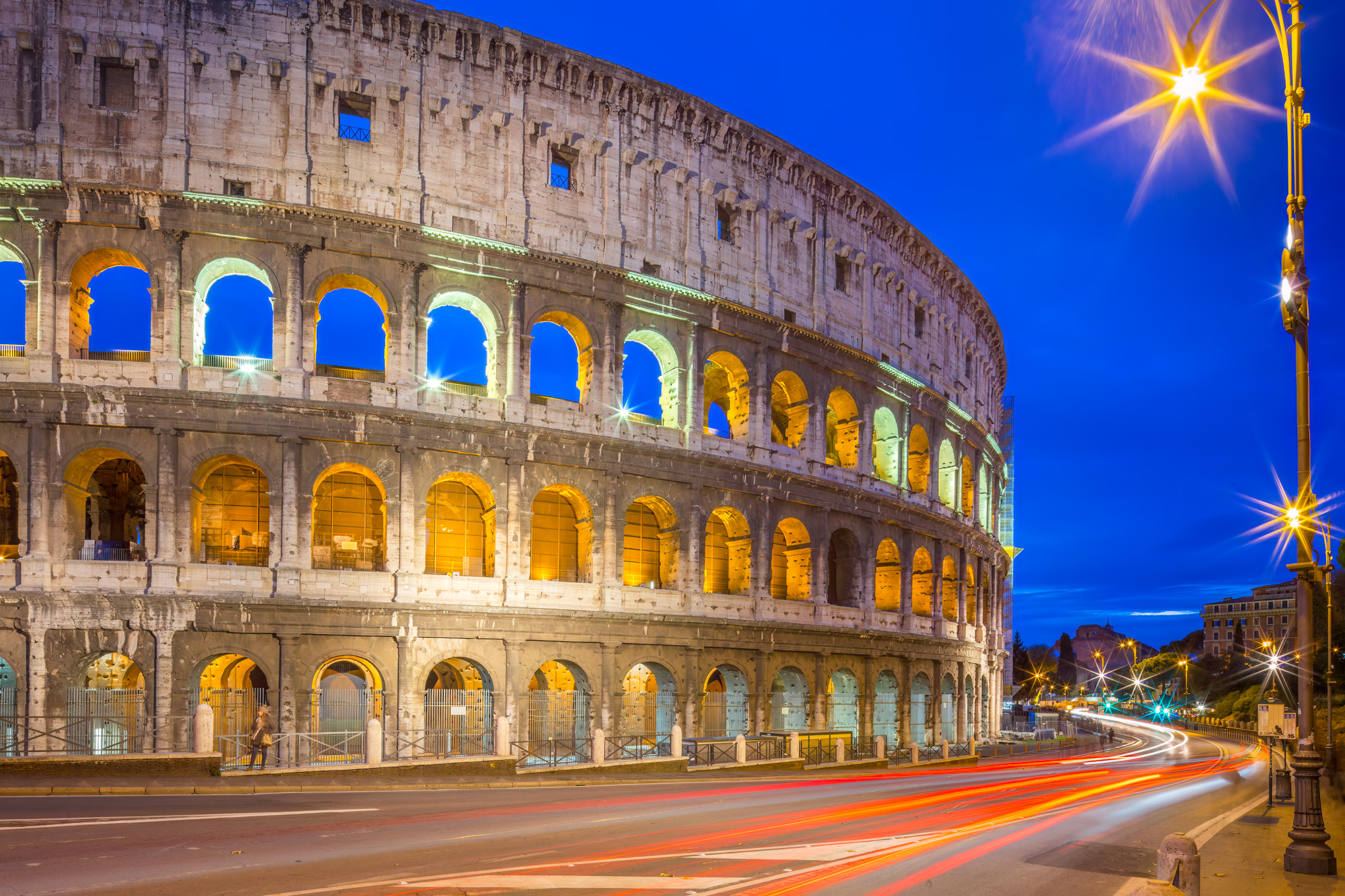 In this striking blue hour photograph of the Colosseum in Rome, Italy, the ancient amphitheater reigns supreme, illuminated with...