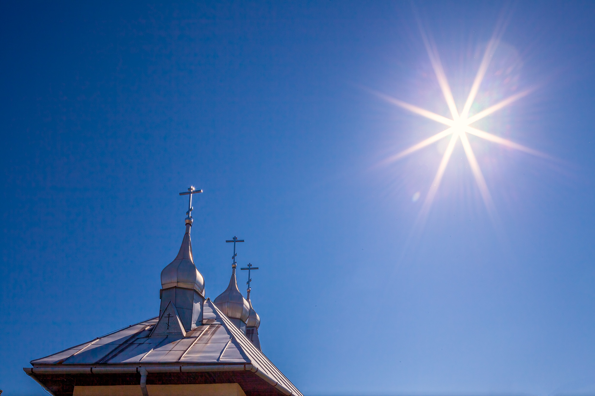 From the heart of Jedlinka, Slovakia, this image frames a radiant sunburst against a flawless blue sky. Amidst this vast azure...