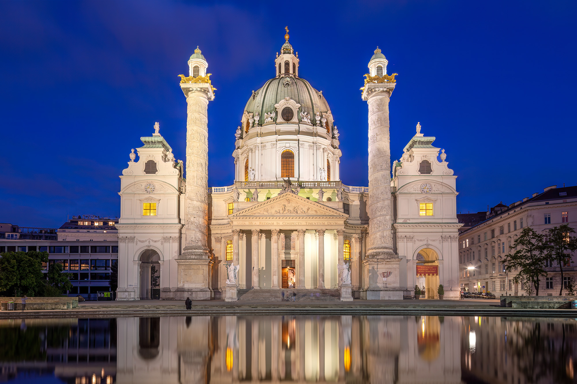 As the day gracefully transitions into the tranquil blue hour, Vienna's Karlskirche emerges as a sublime work of art. This image...