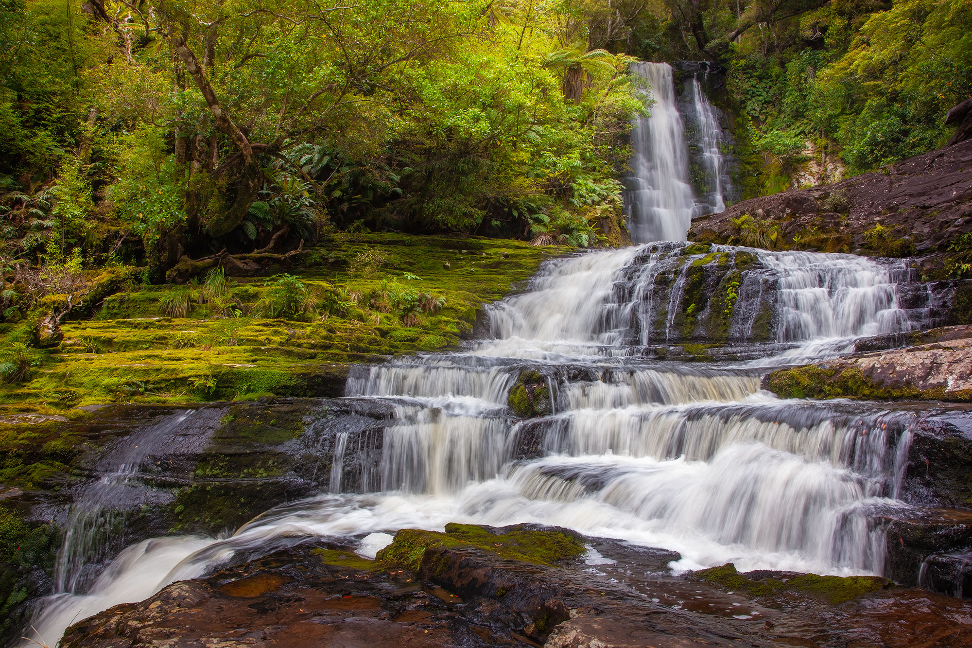 This photograph captures the splendor of McLean Falls in New Zealand. Cascading gracefully through the lush forest, McLean Falls...