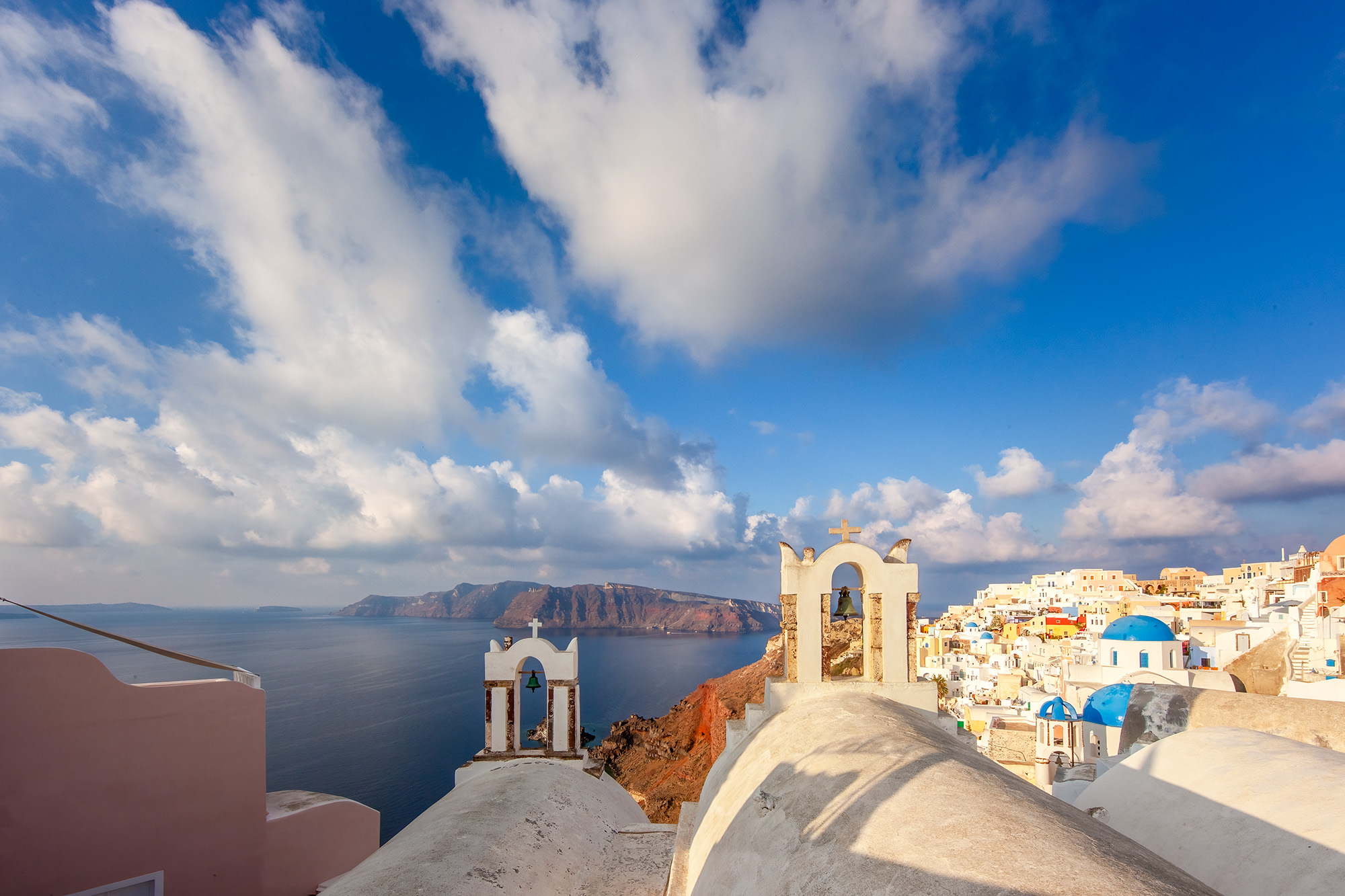 Oia's Belltower Vista One serene morning in Oia, Santorini, Greece, my lens captured a delightful scene. Two elegant belltowers gracefully anchored...
