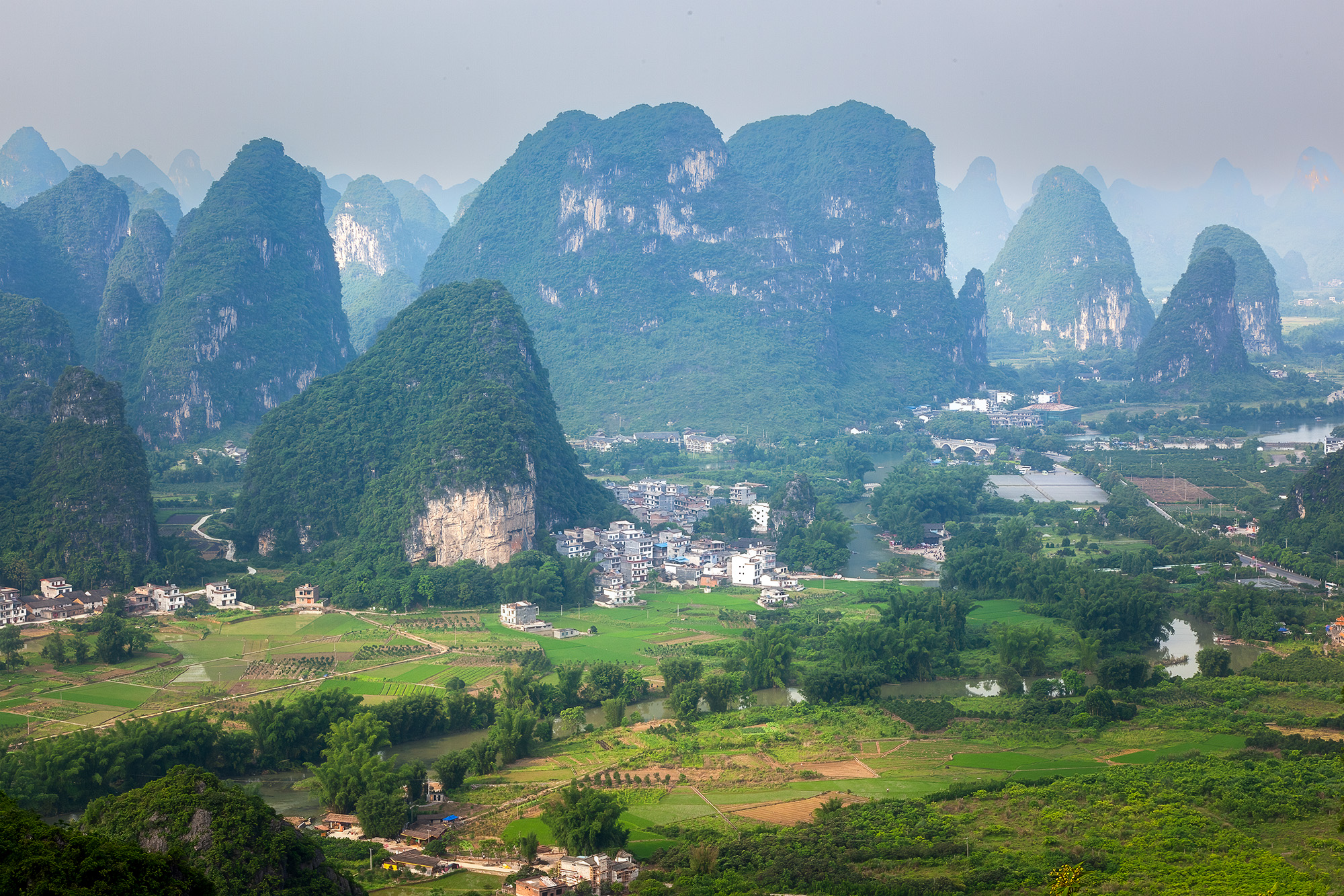This image, captured from the summit of Moon Hill in Guilin, China, offers a panoramic view of lush green mountains and valleys...