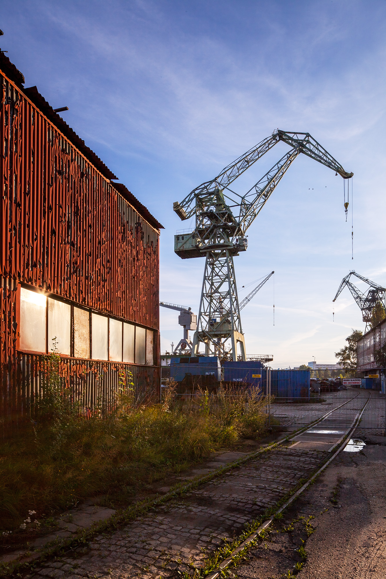 This image, captured from the shipyards of Gdansk, paints a vivid picture of industrial heritage. To the left, a weathered maintenance...