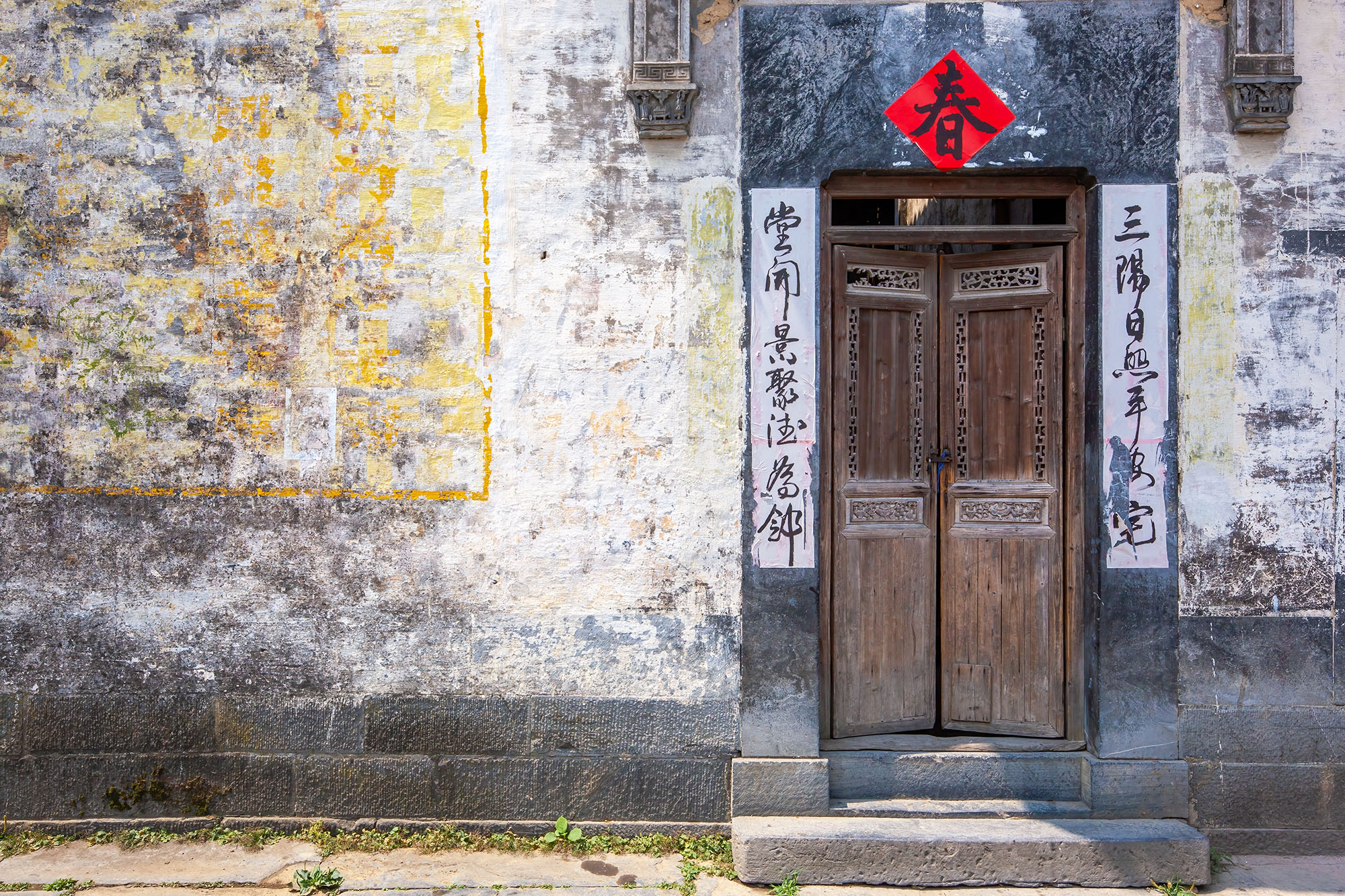 In this image from Xidi, Anhui, China, a doorway beckons with its inscriptions and a red icon overhead. The textures speak of...