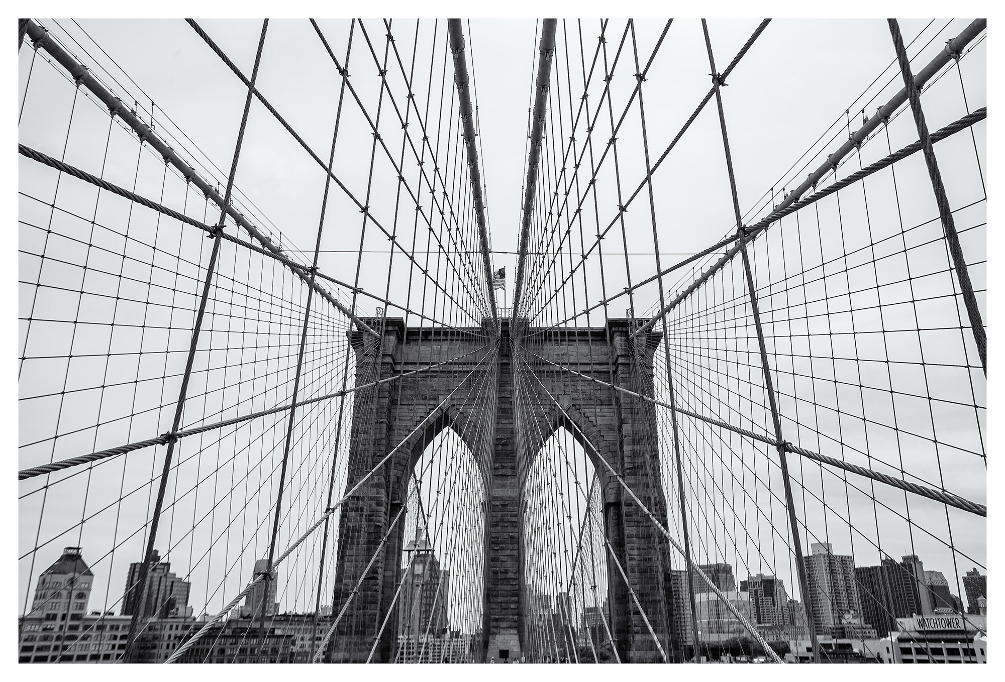 This black and white image captures the Brooklyn Bridge in all its symmetrical glory. While crossing, the intricate web of wires...