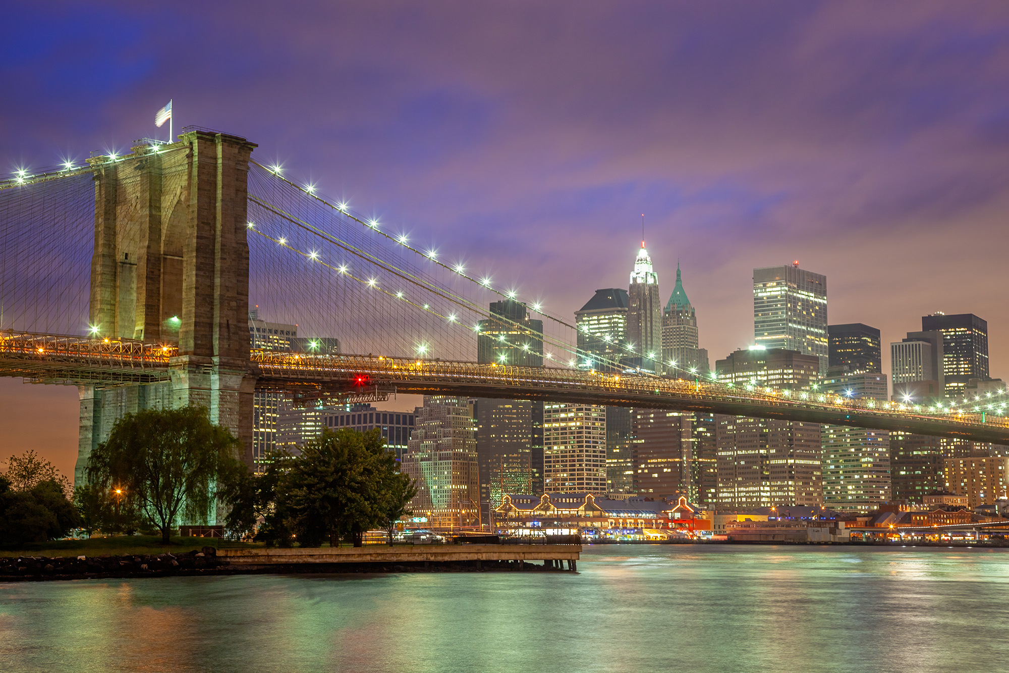 This image captures the Brooklyn Bridge during the enchanting blue hour, spanning the East River from Brooklyn to Manhattan....