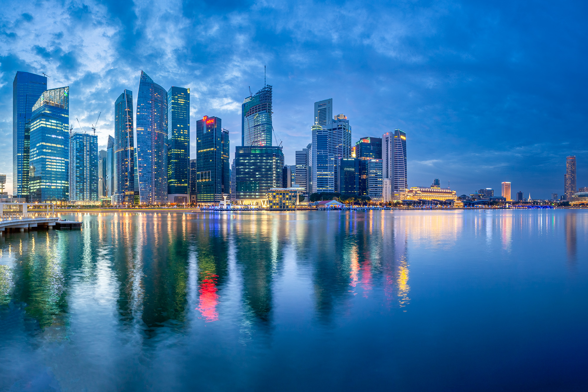 This image, captured during the enchanting blue hour, frames the dynamic Singapore Harbor. It showcases the city's skyscrapers...