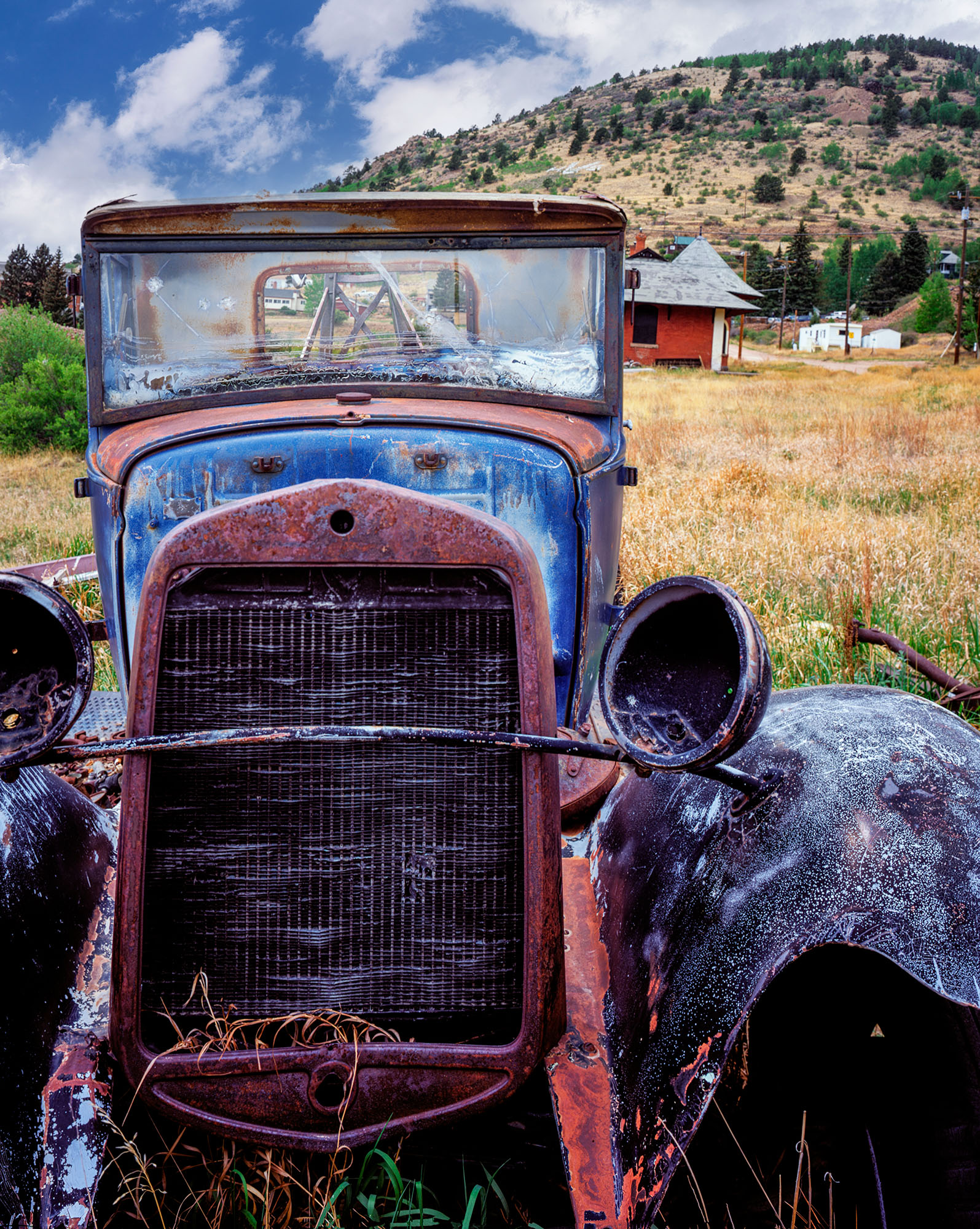 This vertical image, taken in Victor, Colorado, offers a poignant glimpse of an old Ford tow truck, now abandoned in the fields...